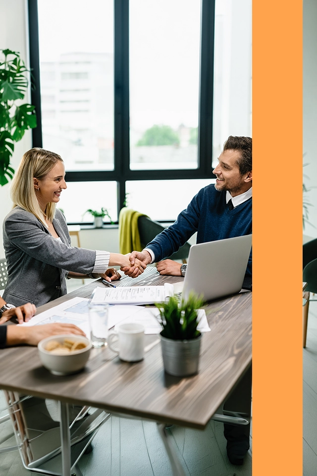 Man och kvinna som skakar hand under en avtalsskrivning.